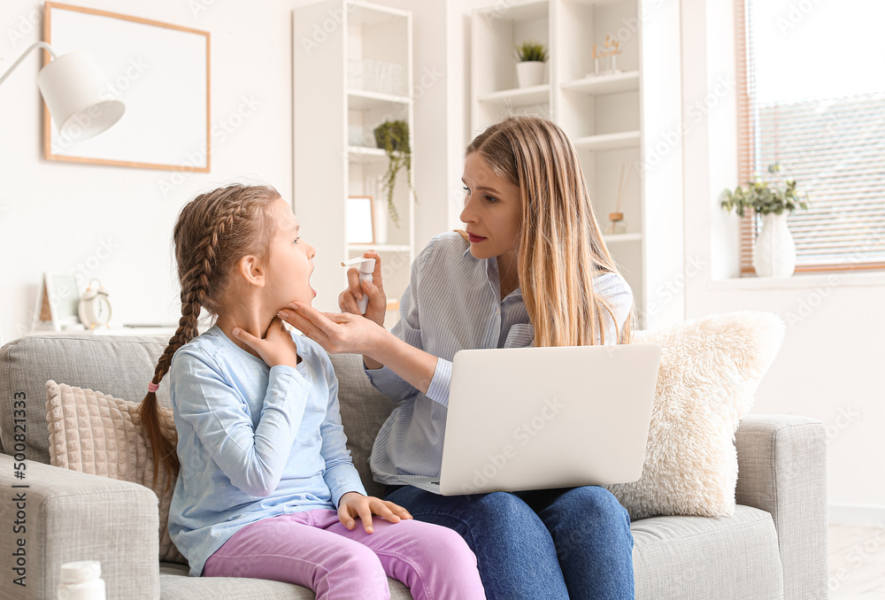 Mother spraying her daughter's sore throat while video chatting with doctor at home Mother spraying her daughter's sore throat while video chatting with doctor at home