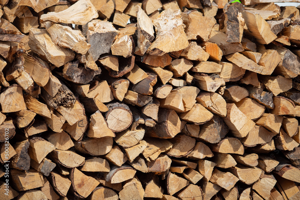 A view of a large pile of chopped firewood for a grilling and smoking. A view of a large pile of chopped firewood for a grilling and smoking.