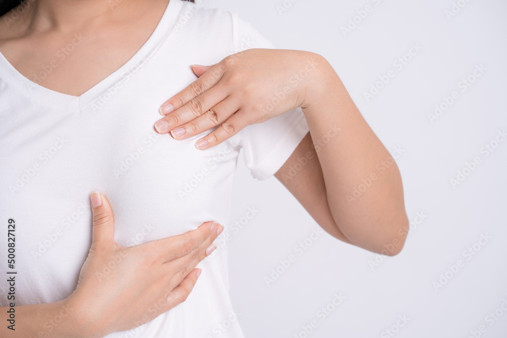 Woman hands checking lumps on her breast for signs of breast cancer on gray background, health care concept. Woman hands checking lumps on her breast for signs of breast cancer on gray background, health care concept.
