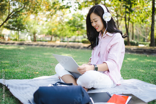 Woman students studying online. She is sitting outdoors.