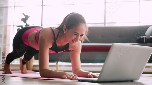 Asian girl is practicing online fitness from home.