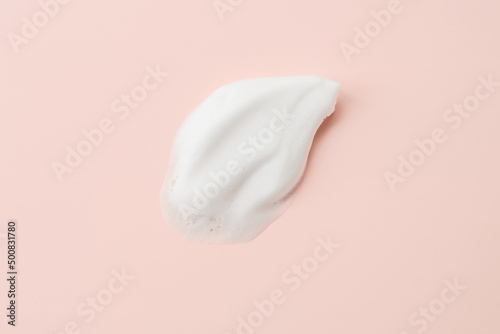 Cleansing foam for face, hands or body. Face cleansing mousse sample texture closeup.. White cleanser foam bubbles on pastel pink background. photo