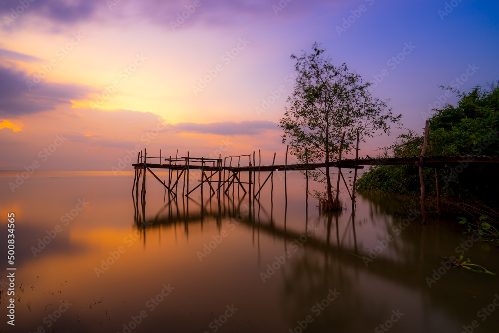 Wooden bridge on river at sunset Wooden bridge on river at sunset