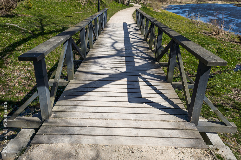 A wooden bridge over a small river on a sunny spring day.A wooden bridge over a small river on a sunny spring day.