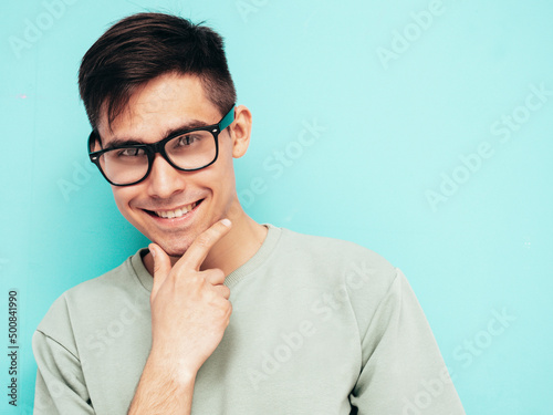 Portrait of handsome smiling model. Sexy stylish man dressed in t-shirt and jeans. Fashion hipster male posing near blue wall in studio. Isolated. In spectacles or eyeglasses