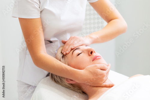 A cosmetologist massages the face of a beautiful adult woman. Rejuvenation and professional cosmetology in the salon