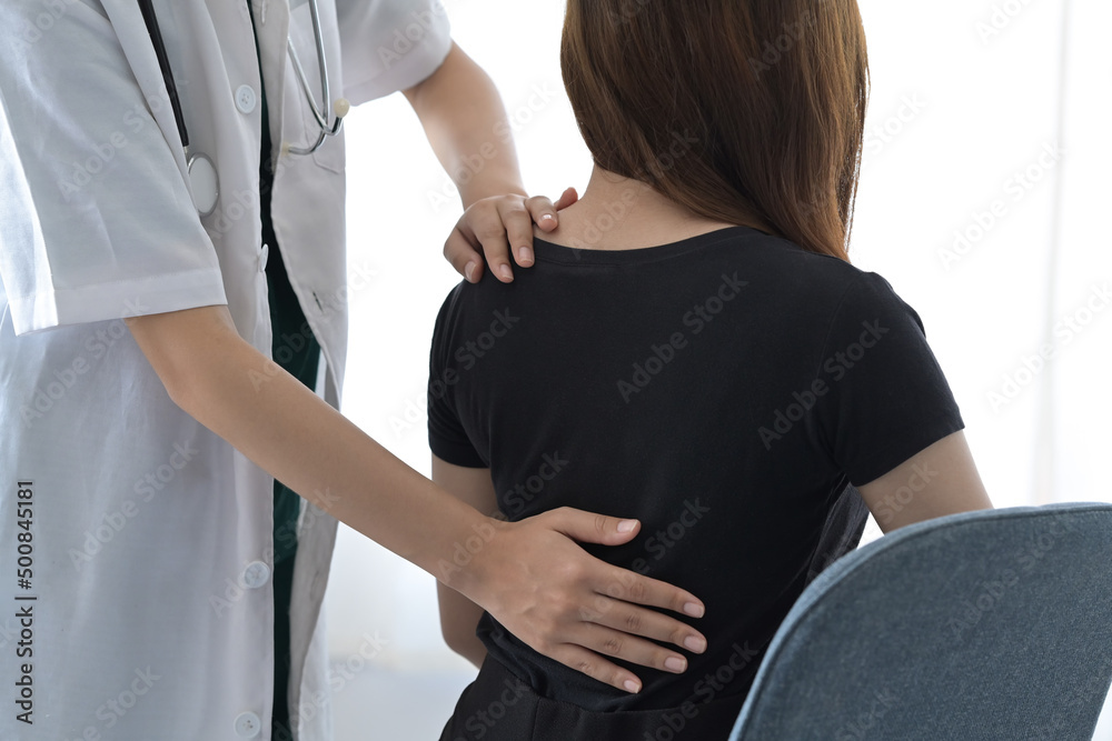 Cropped shot physiotherapist examining female patient injured back in medical clinic.
