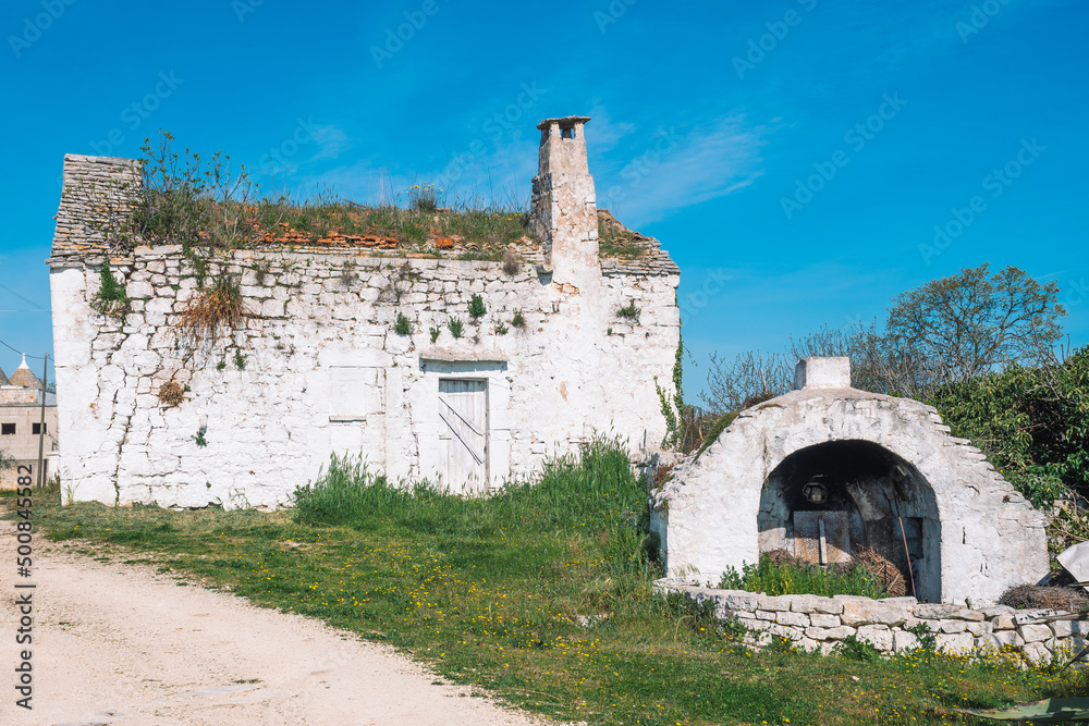 Beautiful white traditional old stone outdoor oven or fireplace in the countryside in Puglia region, Italy with white old farm, finca or cottage
