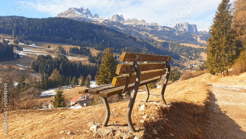 Lonely bench overlooking the mountain landscape of the city of Moena.
