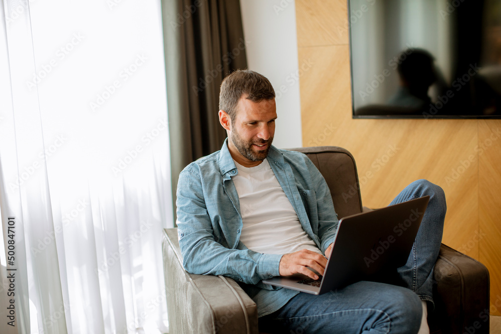 Young man using laptop in the living room Young man using laptop in the living room