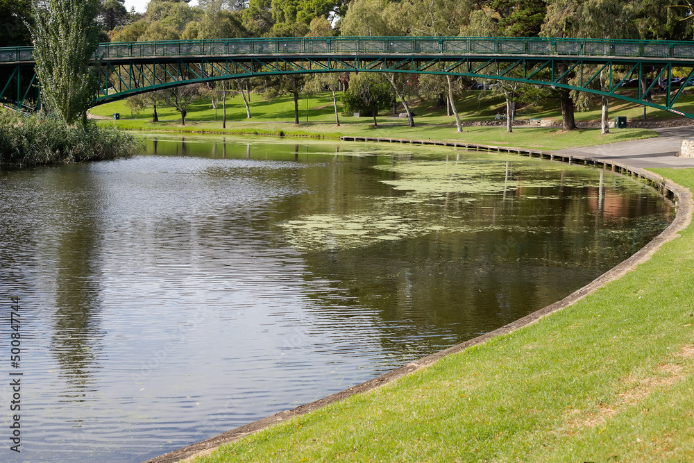 Landscape with a bridge over the river in the city park surrounded by green trees Landscape with a bridge over the river in the city park surrounded by green trees