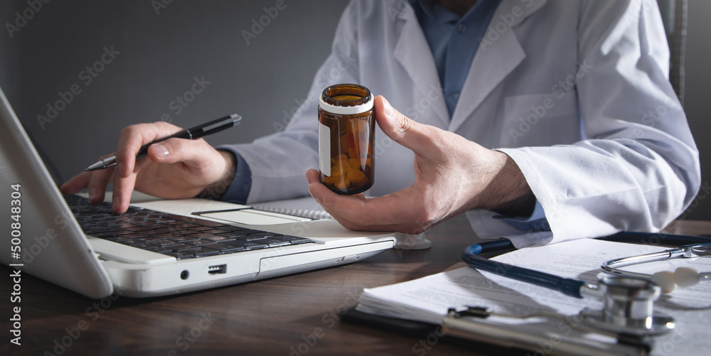 Caucasian doctor holding pill in clinic.