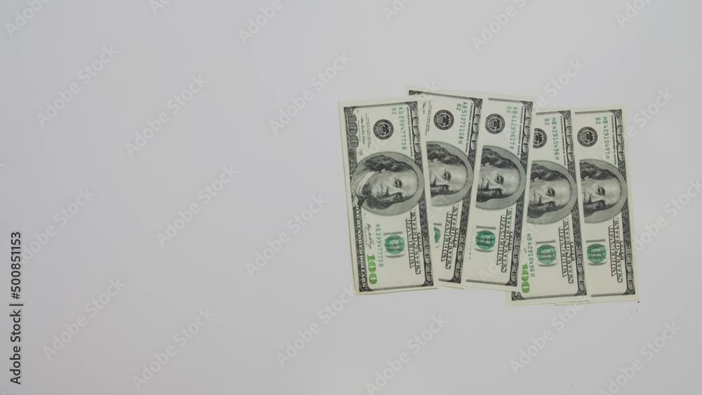 A man's hand quickly puts hundred dollar bills on the table. Then they are collected all together in a pile A man's hand quickly puts hundred dollar bills on the table. Then they are collected all together in a pile
