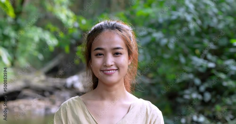 Handheld shot, Close up face of Young pretty woman standing looking to camera with smile on camping site in forest Handheld shot, Close up face of Young pretty woman standing looking to camera with smile on camping site in forest