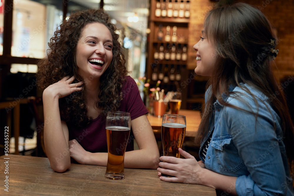 Two happy female friends having beer and socializing in a pub Two happy female friends having beer and socializing in a pub
