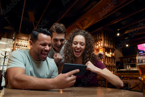 Cheerful soccer fans watching a match on smartphone in a pub