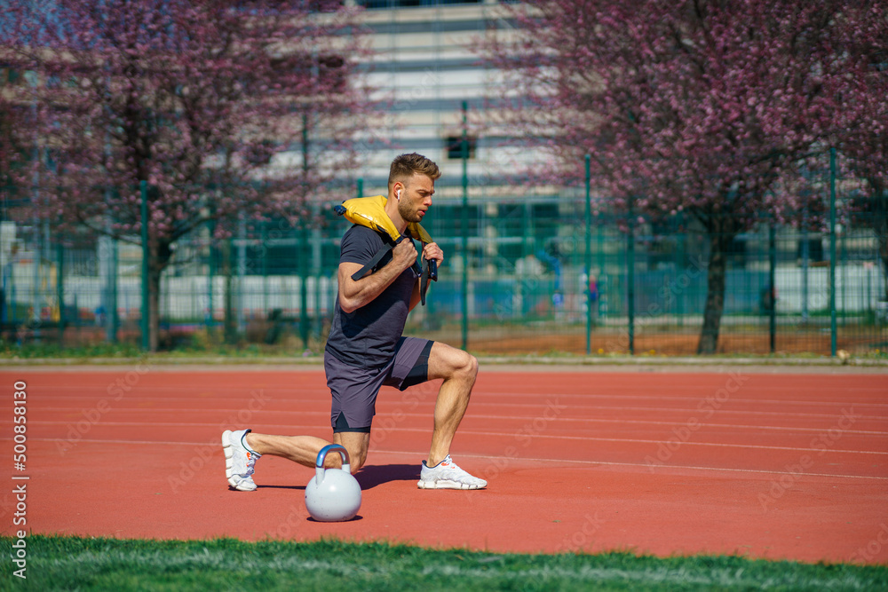 Muscular young man exercising with heavy weight bag in the sport stadium. Sporty man working out with heavy weight bag. Muscular young man exercising with heavy weight bag in the sport stadium. Sporty man working out with heavy weight bag.
