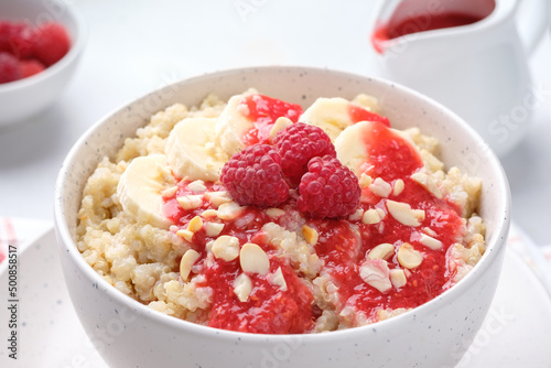 Bowl of quinoa porridge with banana, raspberry sauce and peanuts close-up, soft focus. Healthy breakfast.