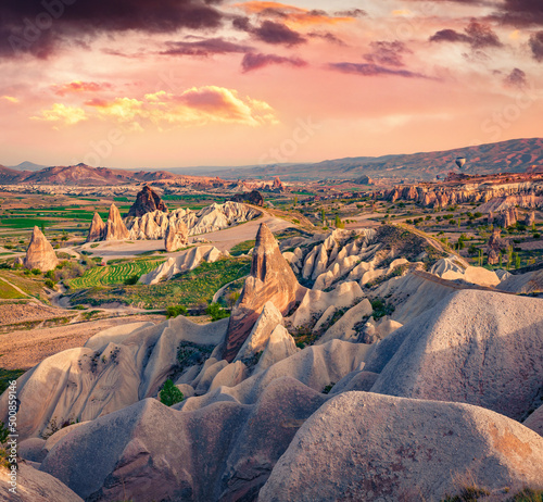 Splendid summer scene of Cappadocia with balloons on background. Colorful outdoor scene in Red Rose valley, Goreme village location, Turkey, Asia. Traveling concept background..