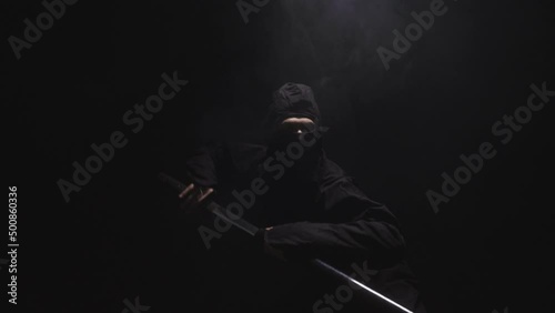 Medieval warrior assassin ninja with sword in aggressive pose in smoke