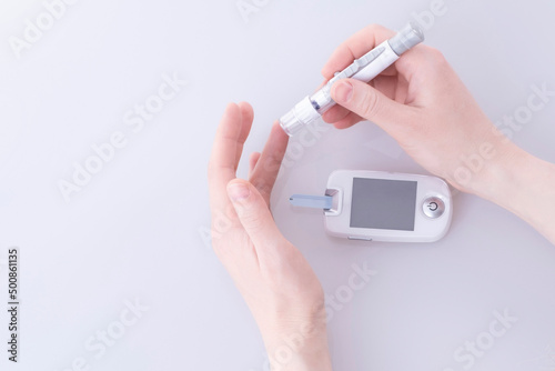 Human using a glucometer to measure and test blood glucose levels from a finger.