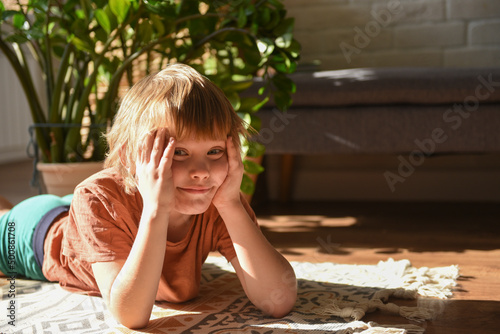 Smiling boy lying down with head in hands at home photo