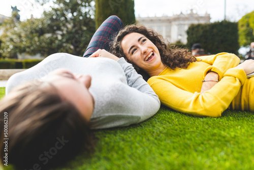 Cheerful young woman lying down with friend at park photo