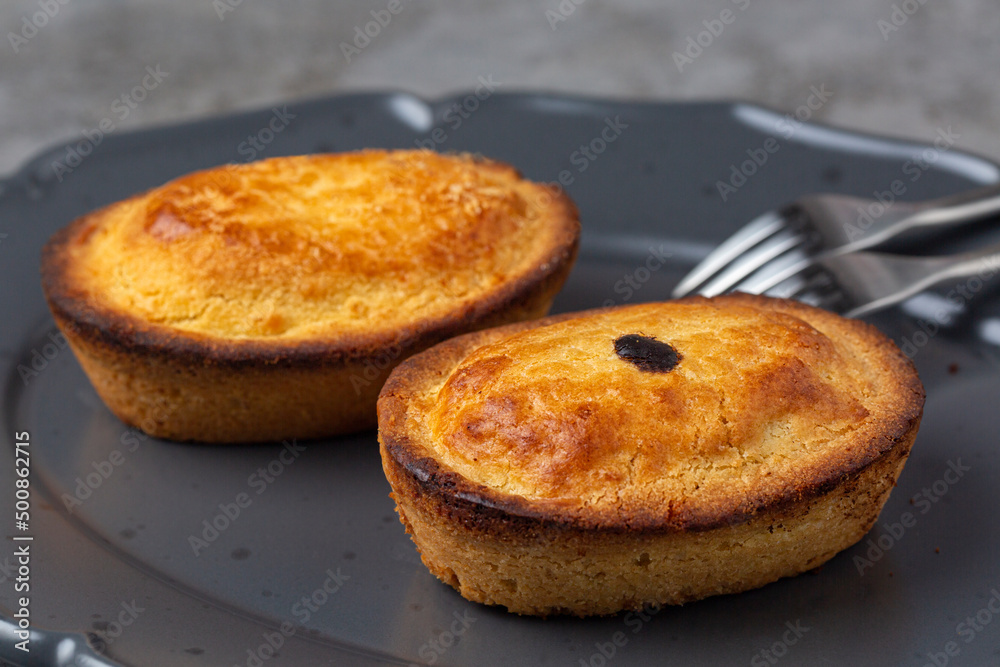 A Pasticciotto, small cake, filled Italian pastry with egg custard cream. Called also pusties. Traditional pastry in Apulia,  typically served for breakfast. Dark gray background.