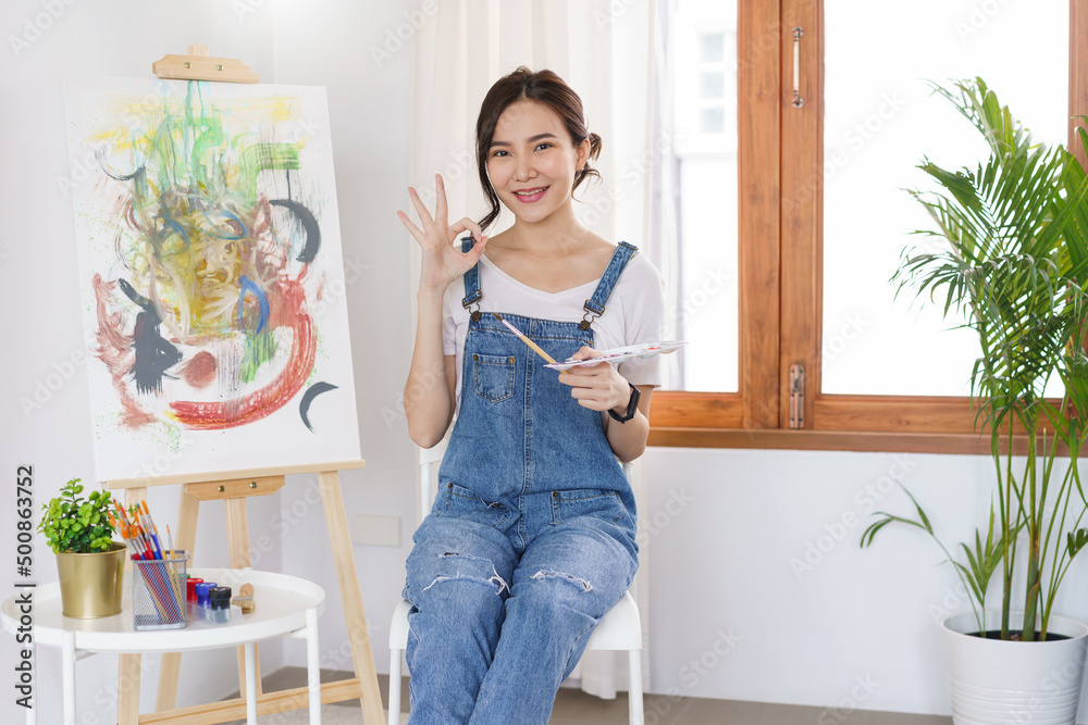 Creative of art concept, Young asian woman gesture to doing ok when drawing the artwork finished