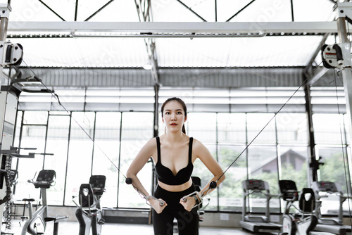 exercise concept The shapely lady standing and concentrating on doing curl pulling down machine with her both hands