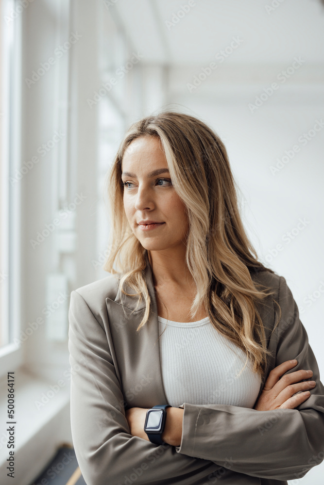 Businesswoman with arms crossed standing in office Businesswoman with arms crossed standing in office