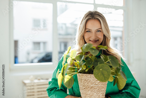 Happy woman houseplant standing in front of window at home
