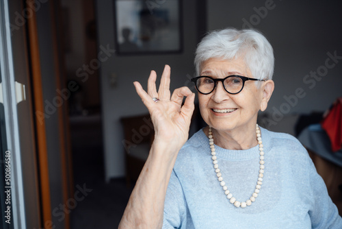 Happy senior woman wearing eyeglasses showing OK sign gesture