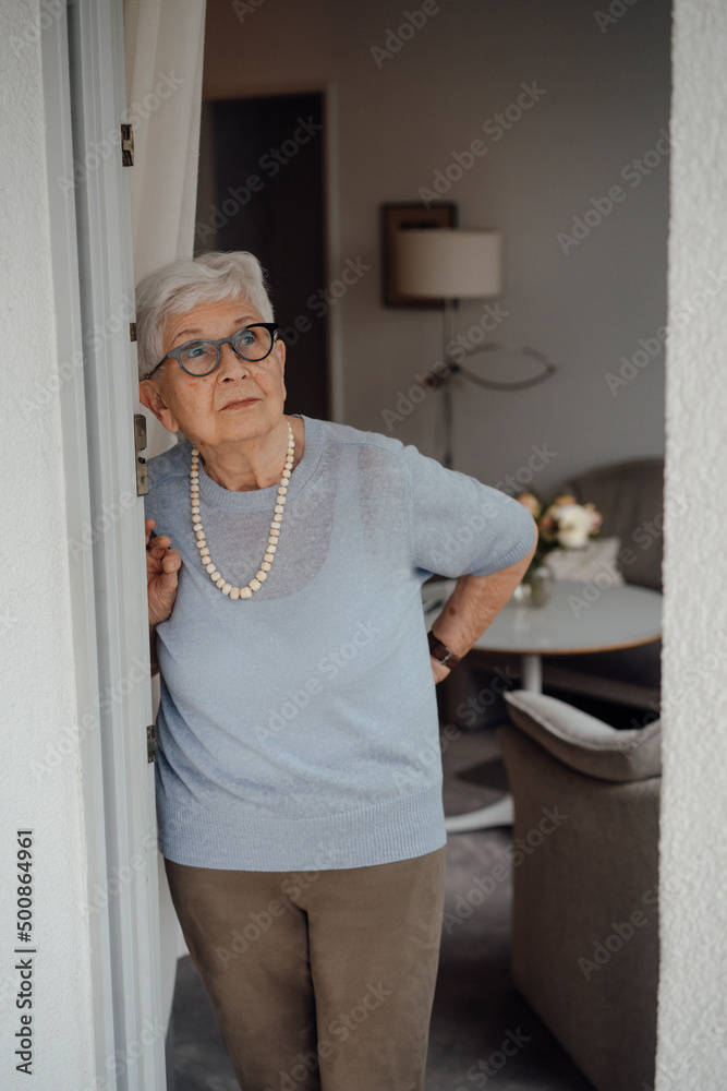 Senior woman with white hair standing at apartment doorway Senior woman with white hair standing at apartment doorway