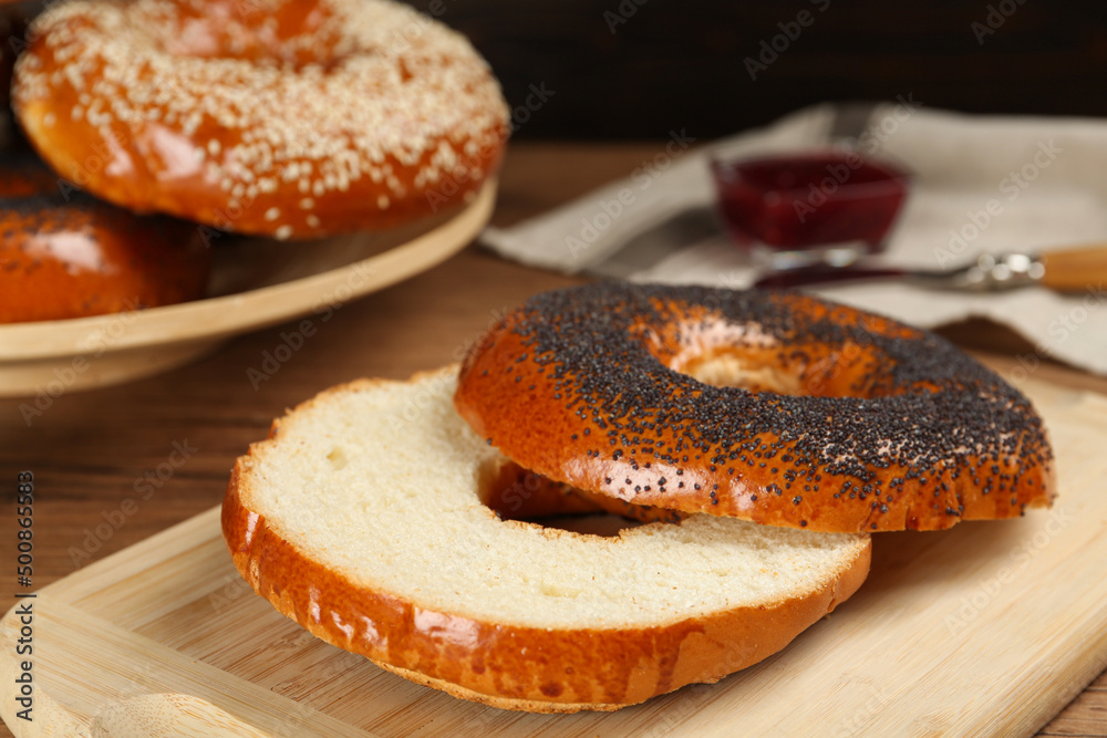 Delicious fresh halved bagels on wooden board, closeup
