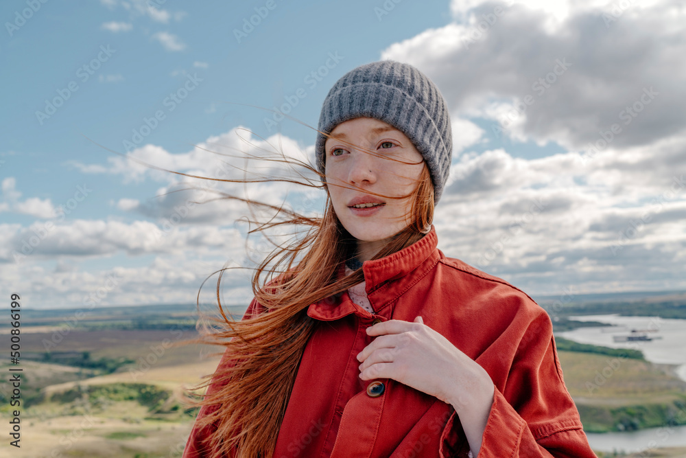 Young woman with knit hat standing under cloudy sky Young woman with knit hat standing under cloudy sky