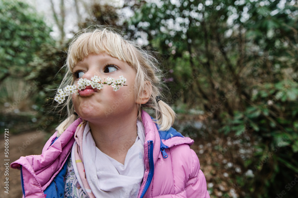 Cute girl making mustache with white flowers Cute girl making mustache with white flowers