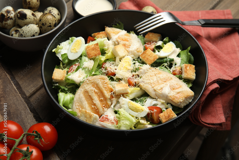 Delicious Caesar salad in bowl on wooden table Delicious Caesar salad in bowl on wooden table