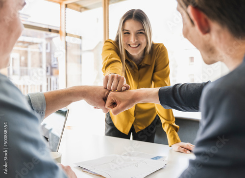 Happy business team touching fists in office photo