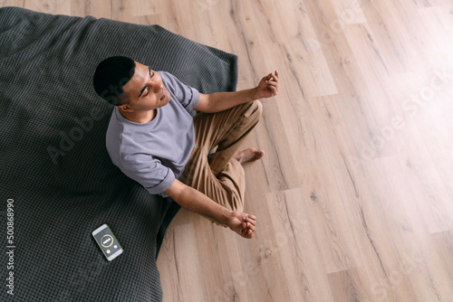 Young man practicing breathing exercise by smart phone with timer at home photo