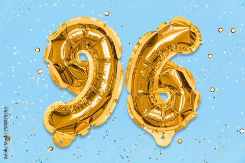 The number of the balloon made of golden foil, the number ninety-six on a blue background with sequins. Birthday greeting card with inscription 96. Numerical digit. Celebration event, template