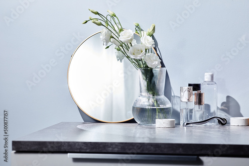 Stampa su tela Toilet table for woman with mirror, cosmetics and flowers in vase in bathroom