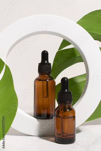 Dropper bottle with monstera palm leaf. Aromatic oil container  medical packaging template. Herbal cosmetic concept.