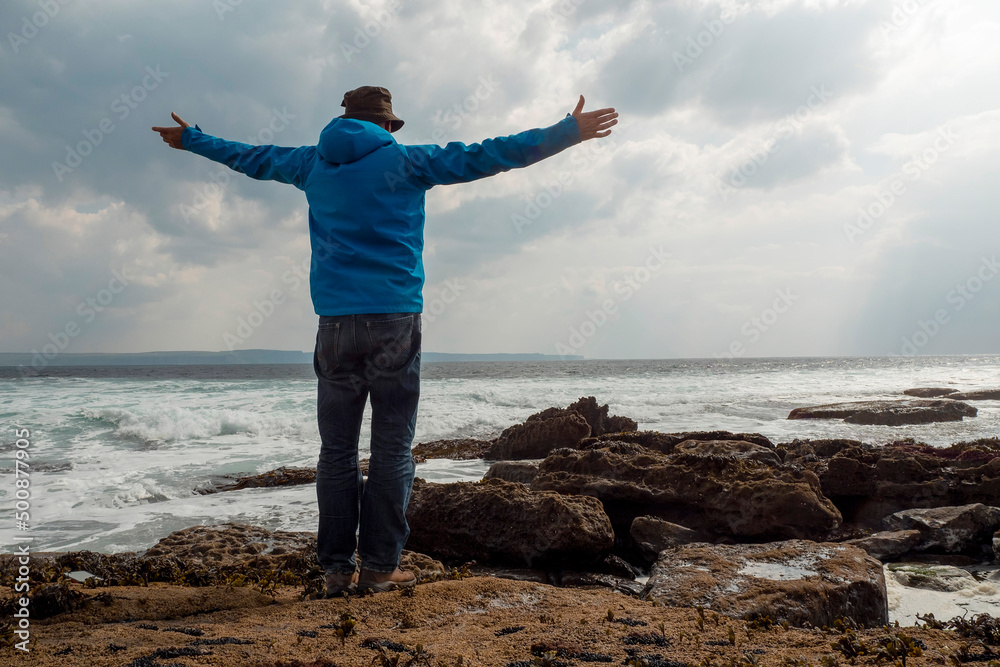 Male tourist standing on a rough stone coast. Aran island, county Galway, Ireland. Blue cloudy sky in the background. Travel and tourism concept. Beautiful Irish landscape in the background. Male tourist standing on a rough stone coast. Aran island, county Galway, Ireland. Blue cloudy sky in the background. Travel and tourism concept. Beautiful Irish landscape in the background.