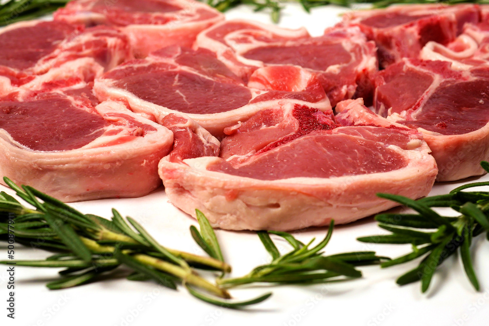 Fresh lamb chops and green rosemary herb on white background. Meat industry product. Butcher craft