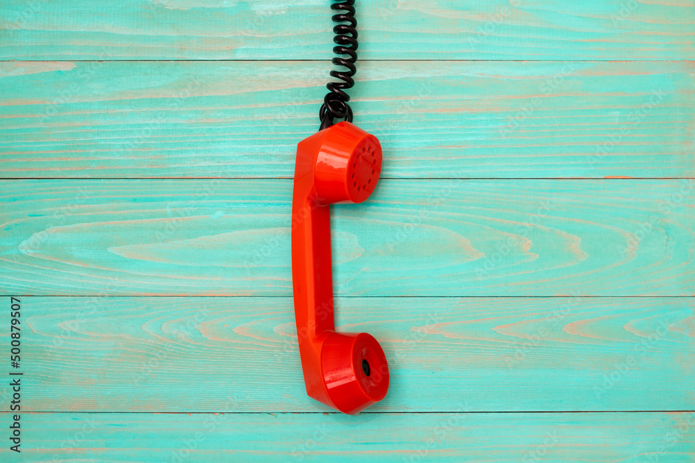Orange corded telephone handset on blue background
