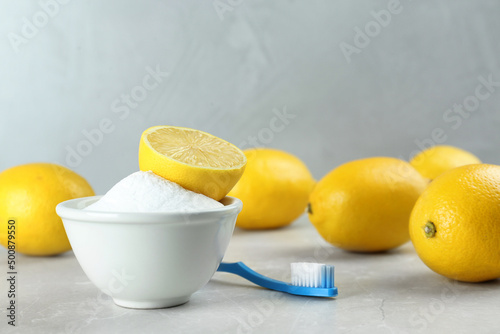 Toothbrush, lemons and bowl of baking soda on light grey table