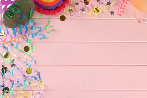 Flat lay composition with colorful serpentine streamers and confetti on pink wooden table, space for text