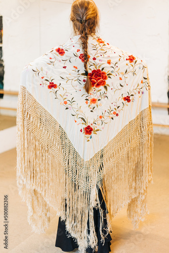 female flamenco dancer with her back to the stage wearing a shawl and braided hair