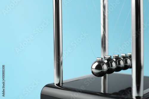 Newton's cradle on light blue background, closeup. Physics law of energy conservation